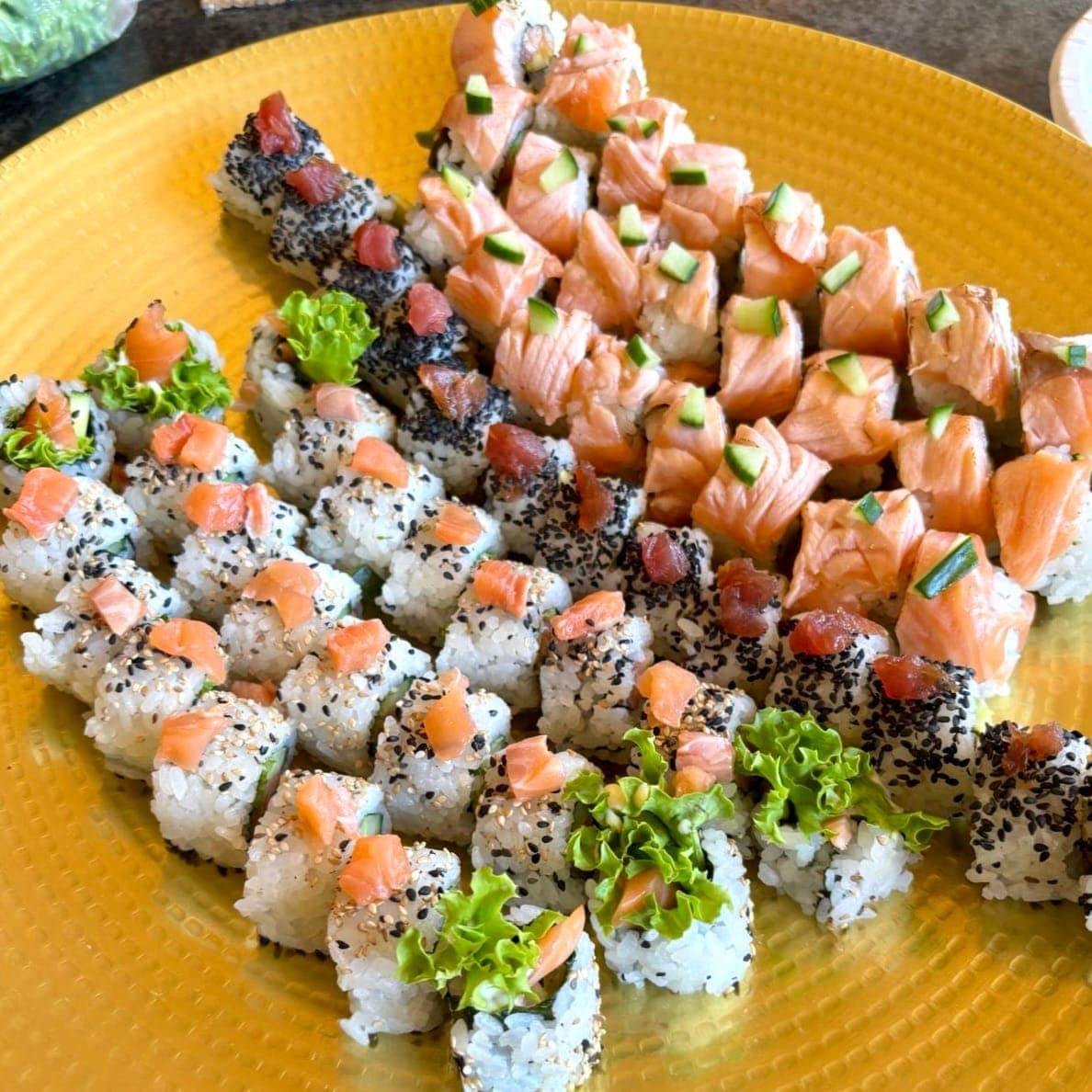 Frisch zubereitete Sushi-Rollen mit Lachs auf goldenem Teller